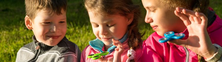 Three children sitting together playing with fidget toys