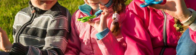 Three children sitting together playing with fidget toys