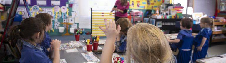Child raises hand in classroom
