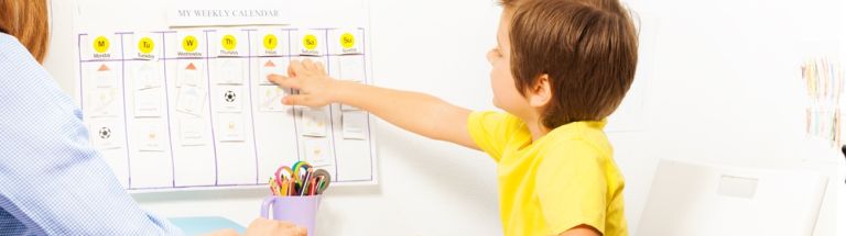 Young boy pointing at schedule on wall