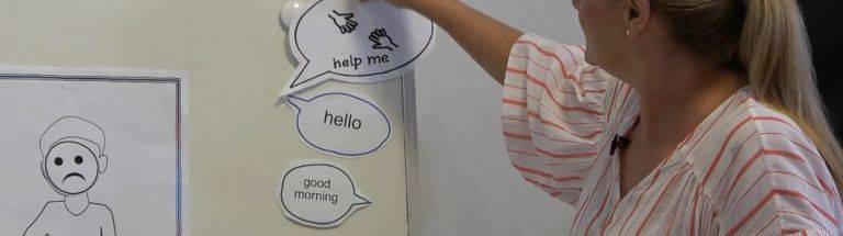 Teacher sticking 'help me' sign onto whiteboard