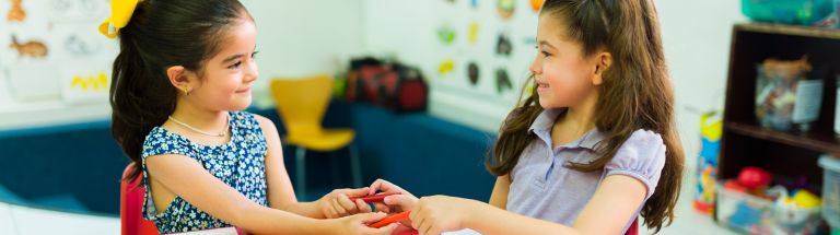 Two young girls sharing pencils