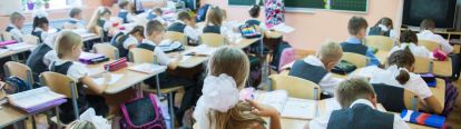 Classroom full of students sitting at their desks with a teacher at the blackboard