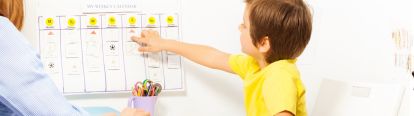 Young boy pointing at schedule on wall