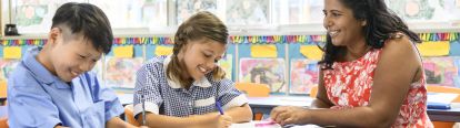Teacher smiling while watching students write