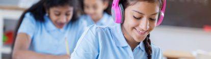 Female student completing work with headphones on head.