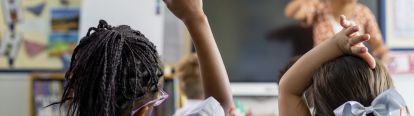 Students holding their hands up to answer questions.