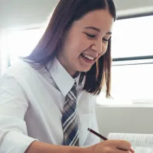 Two high school students smiling while writing in classroom