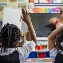 Students holding their hands up to answer questions.