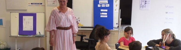 Teacher standing while young students are at desks