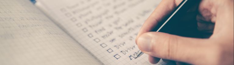 A person writing a checklist in a notebook