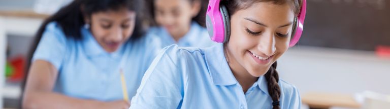 Female student completing work with headphones on head.